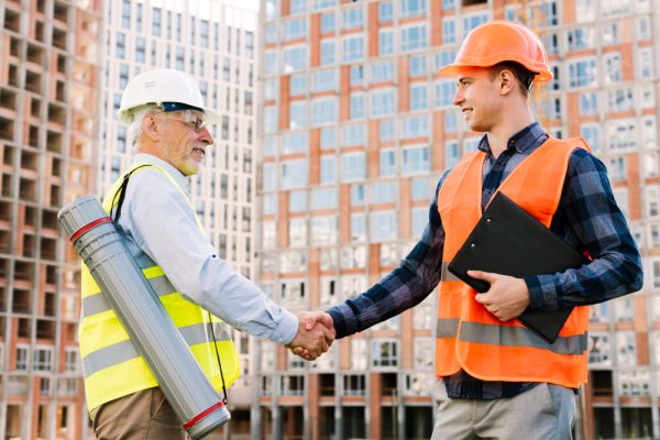 side-view-men-with-safety-vests-shaking-hands